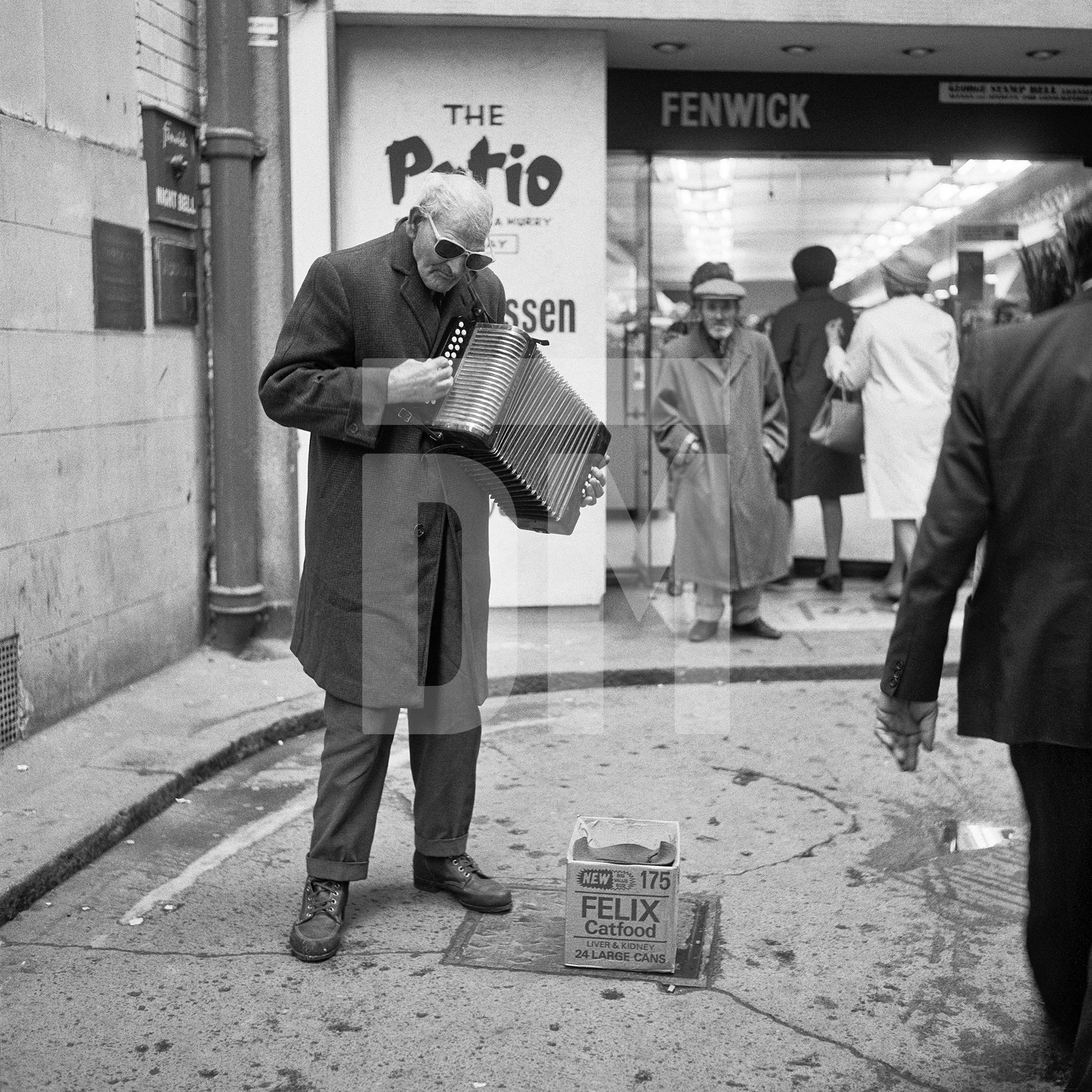 Blind accordion player, busking outside deprtment store, Newcastle upon Tyne. September 1974 by Daniel Meadows