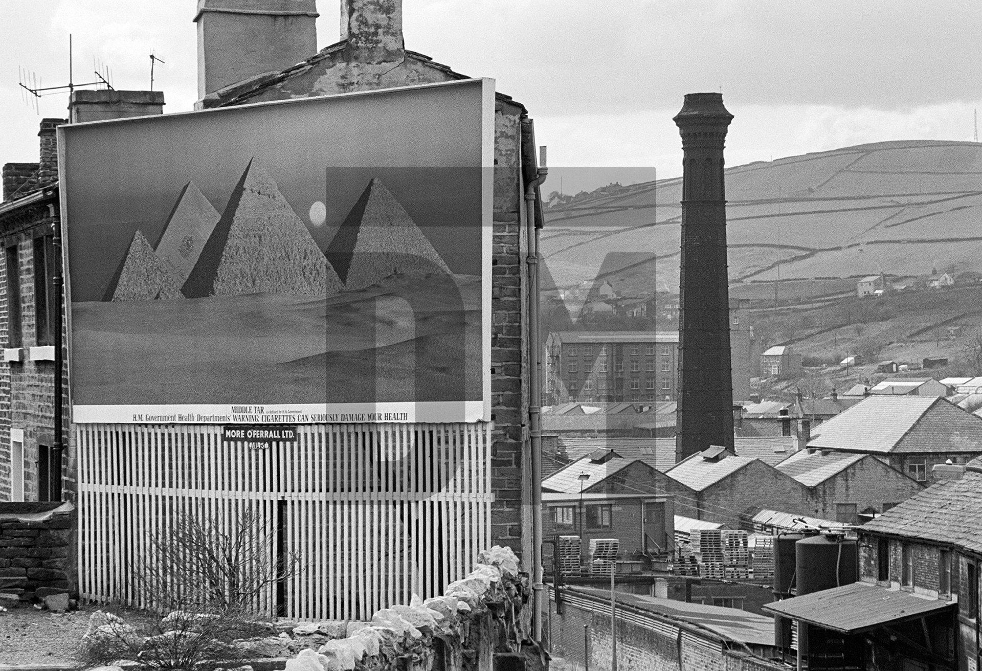 Pyramids, billboard, mill chimney, Colne Valley, West Yorkshire. April 1978 by Daniel Meadows