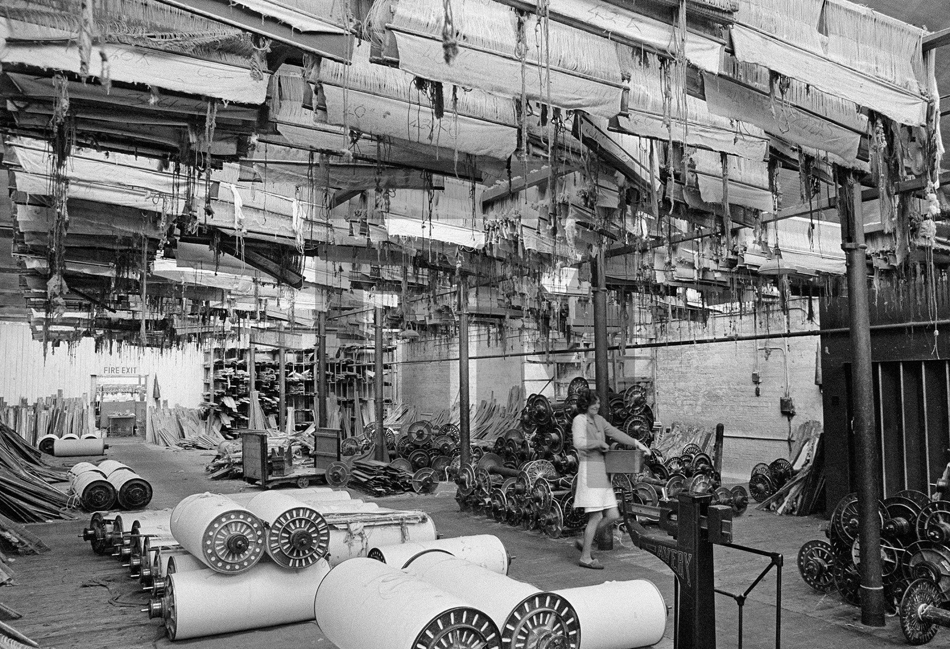 In the warehouse, upstairs with stored loom parts and patterns — healds, reeds and warp beams. March 1977 by Daniel Meadows