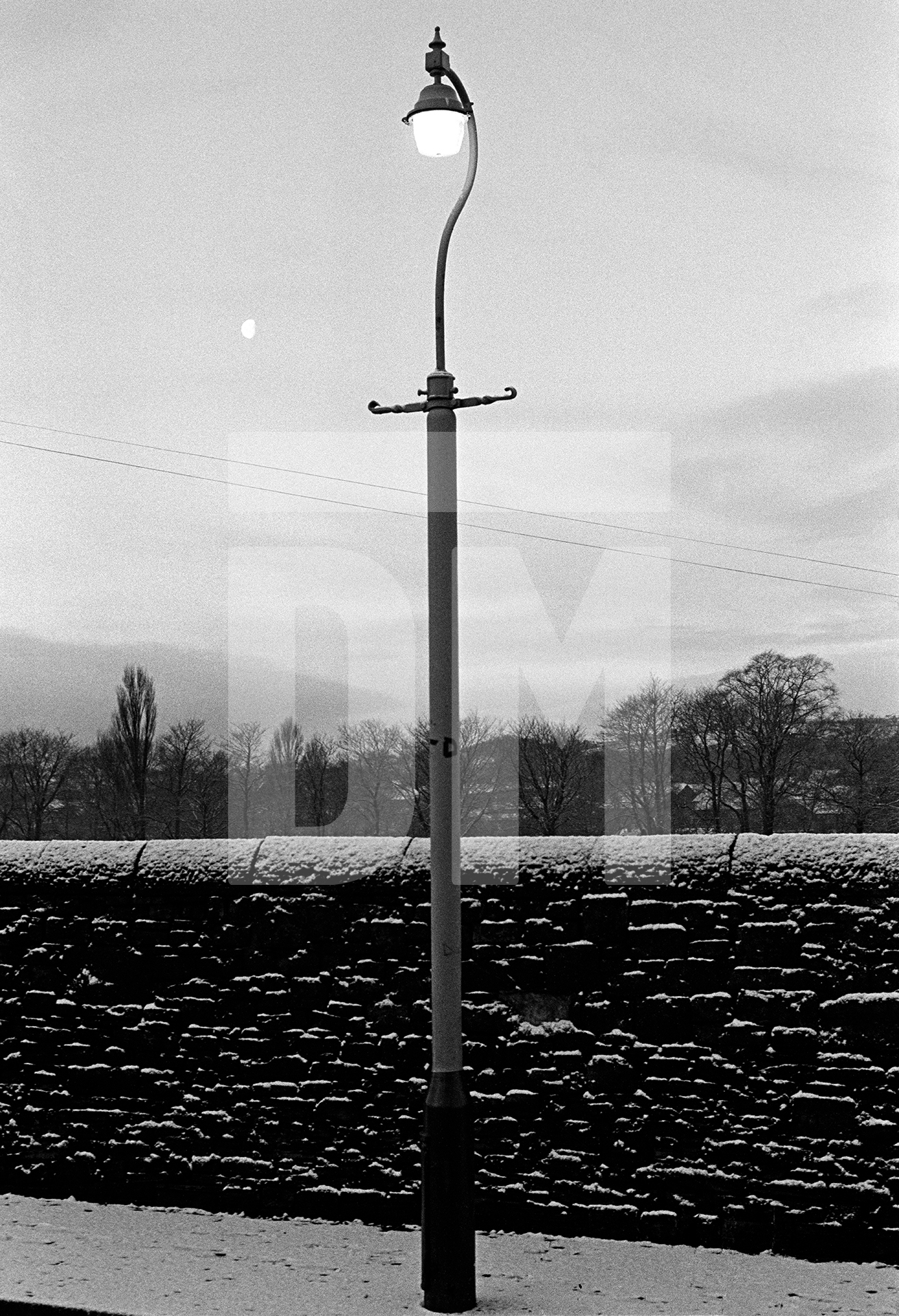 Street lamp, moon and snow, twilight, Nelson, Lancashire. January 1977 by Daniel Meadows