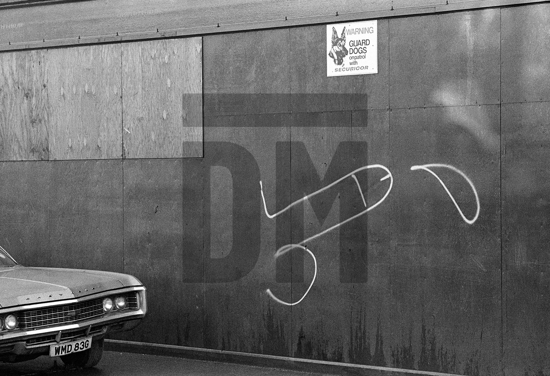 WMD (weapons of mass destruction) registration plate on American car, guard dog warning sign and white graffiti penis, Hull. November, 1981 by Daniel Meadows